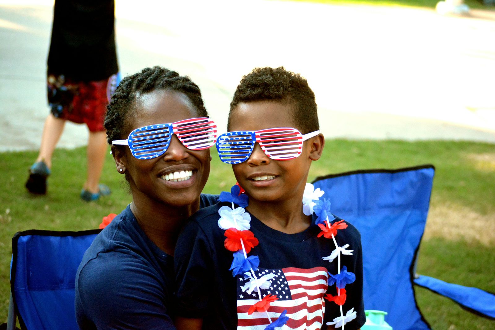Smiling mother and son wearing stars-and-stripes novelty glasses outdoors