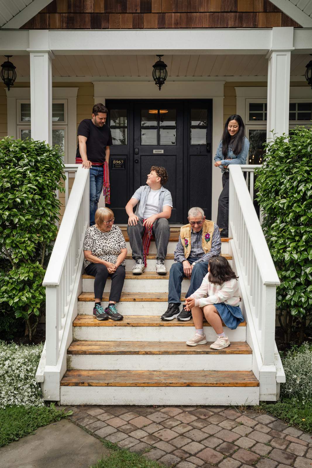 Three generations of a family sitting together on the porch steps of their home